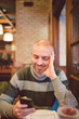 © ramonespelt - Adult man looking at his smartphone in a restaurant