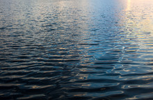 Water Surface With Ripples And Sunrays Reflections