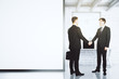 © Who is Danny - Businessmen shake hands in loft office with blank white wall, mo