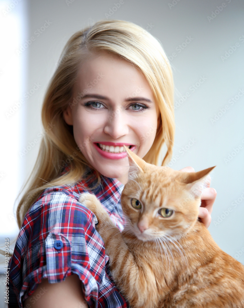 Young woman posing with red cat in hands, close up