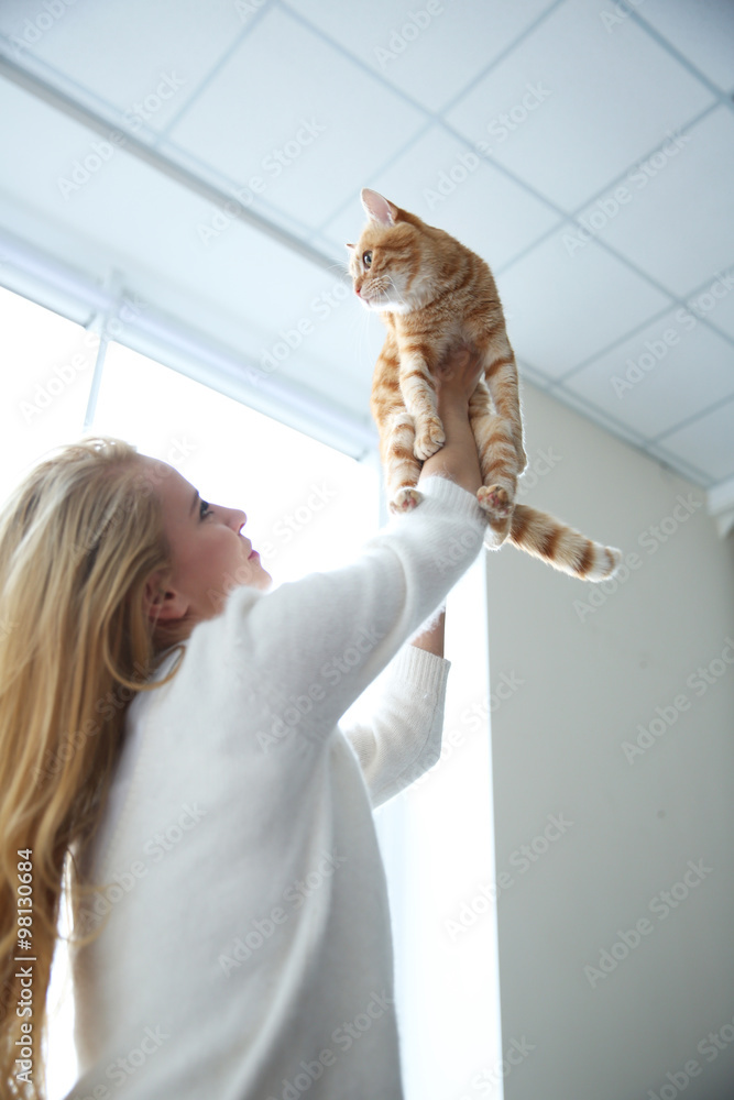 Young woman playing with red cat, close up