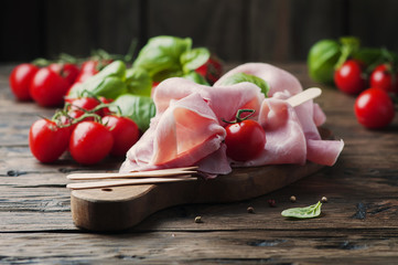 Italian traditional prosciutto with tomato and basil on the wood