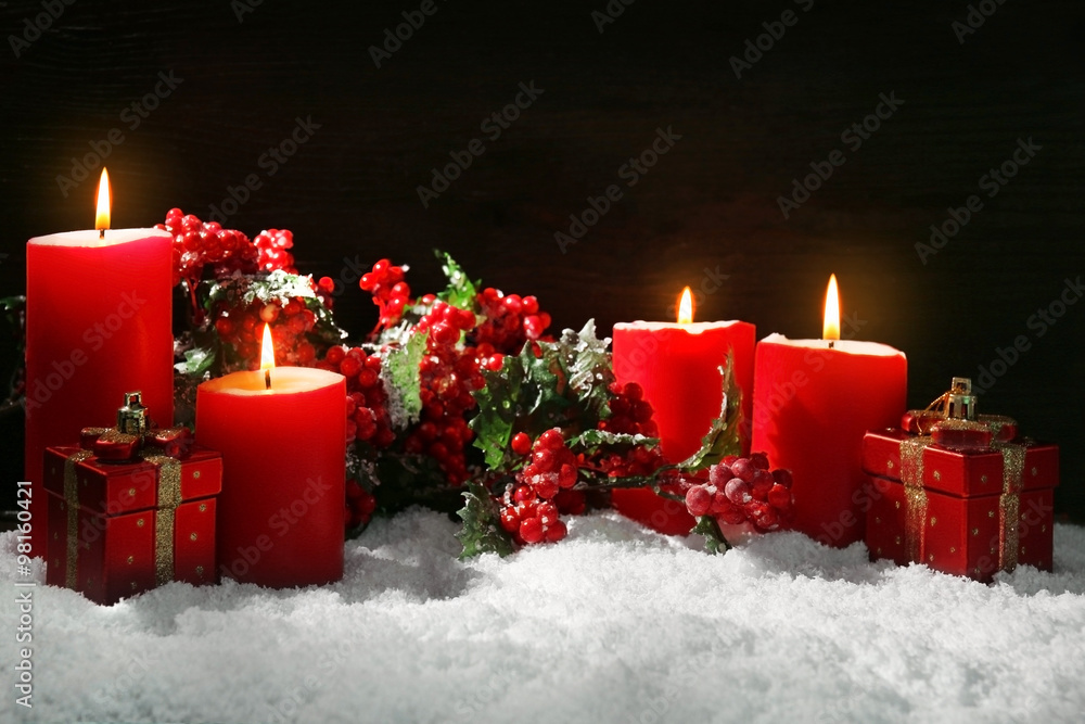 Burning candles, rowan and gift box with snow on wooden background