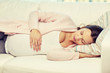 © Syda Productions - happy pregnant woman sleeping on sofa at home