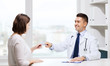 © Syda Productions - smiling doctor giving pills to woman at hospital