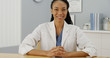 Black woman doctor sitting at desk smiling