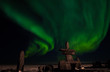 the aurora borealis, behind an inuit structure, with photographers enjoying the northern lights.