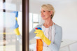 © michaeljung - senior woman cleaning window glass