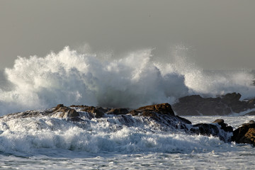 Splash of a stormy sea wave breaking against rocks