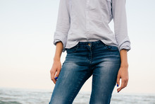 Woman In A Striped Shirt And Blue Jeans Standing On Sea Backgrou