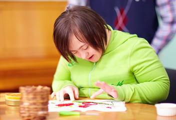 Wall Mural - young adult woman with disability engaged in craftsmanship in rehabilitation center