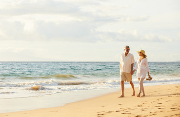 mature couple walking on the beach at sunset