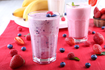 Canvas Print - Milkshakes with berries at red textile on light background