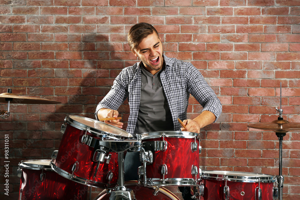 Musician playing the drums on brick wall background