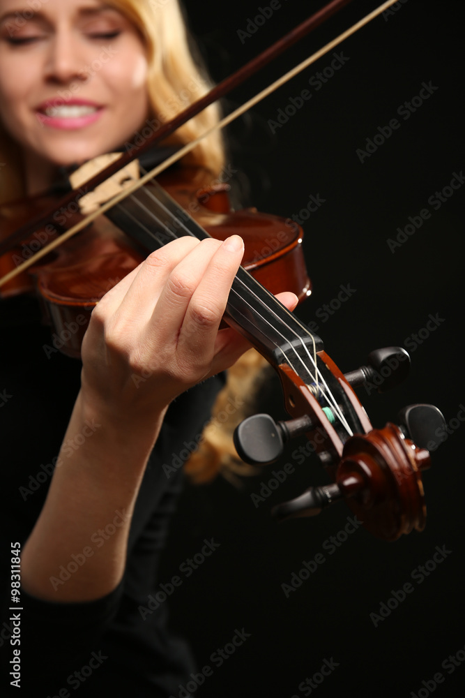 Musician plays violin on black background, close up