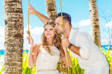 Beautiful young bride in a white dress and groom under a palm tr