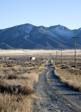 Gravel And Dirt Road Leads To Mountain With Snow In The Nevada D