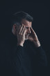 © Westend61 - Portrait of man with hands on his temples in front of black background