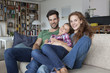 © Westend61 - Portrait of happy couple and little daughter on the couch at home
