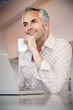 © Westend61 - Portrait of smiling man with earphones and laptop holding credit card