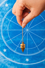 Wall Mural - hand holding a pendulum against an astrological background