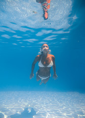 Wall Mural - Young woman swimming underwater