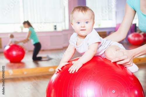 Fototapeta Mother with happy baby doing exercises with gymnastic ball