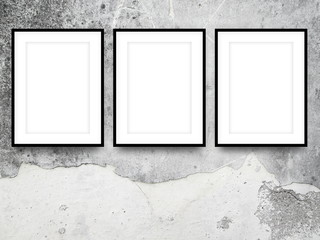 Close-up of three black picture frames on grey weathered concrete wall