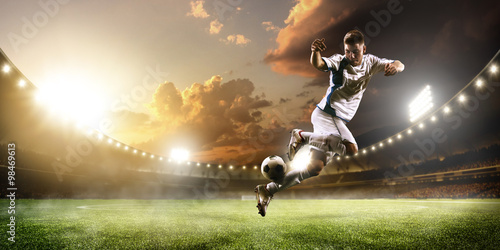 Soccer player in action on sunset stadium panorama background