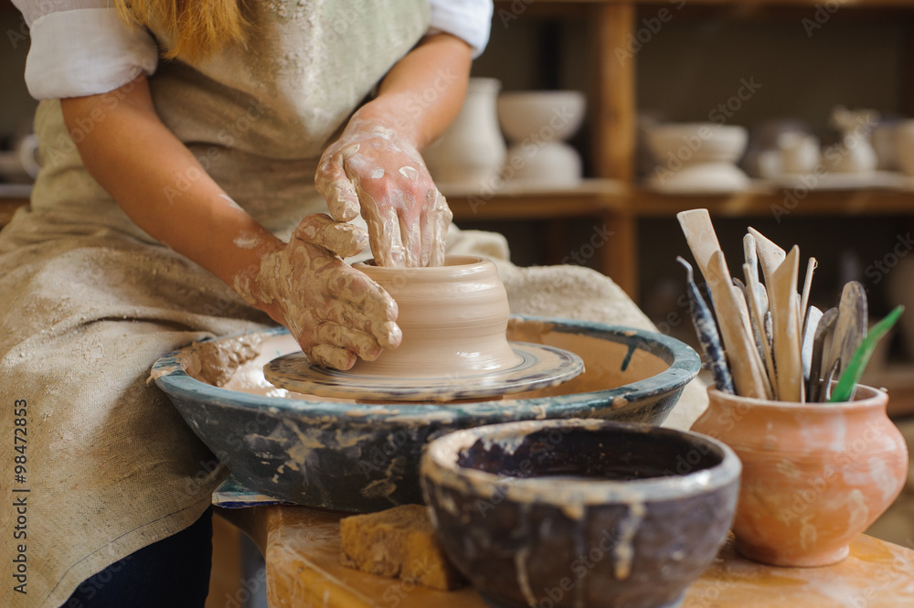hands of a potter, creating an earthen jar on the circle - obrazy, fototapety, plakaty 