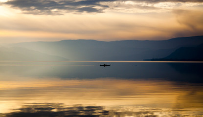 Lone Kayaker on Still Water in Mountains