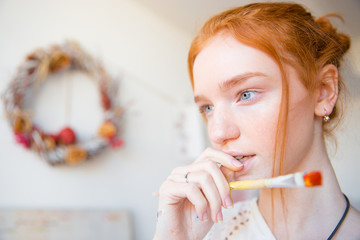 Canvas Print - Pensive beautiful young female holding paintbrush and thinking