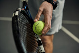 Fototapeta  - Close-up of male hand holding tennis ball and racket. Professional tennis player starting set. 