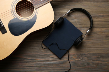 Wall Mural - Acoustic guitar, headphones, notebook and microphone on wooden background, close up