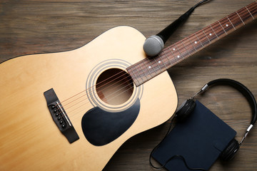 Wall Mural - Acoustic guitar, headphones, notebook and microphone on wooden background