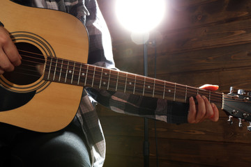 Wall Mural - Guitarist plays guitar on wooden background, close up