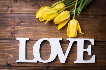 Fresh spring yellow tulips  flowers and word love on dark  woode