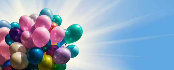 Multi-colored balloons against blue sky with sun light