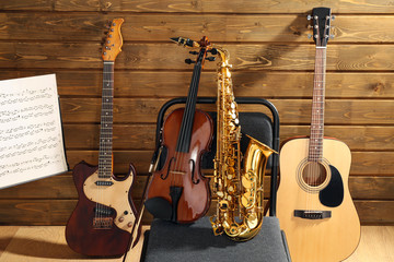 Musical instruments on a chair and note holder against wooden background