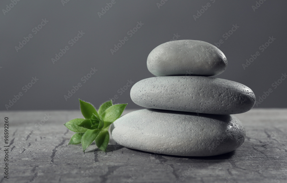 Pile of pebbles with leaf on the table against grey background