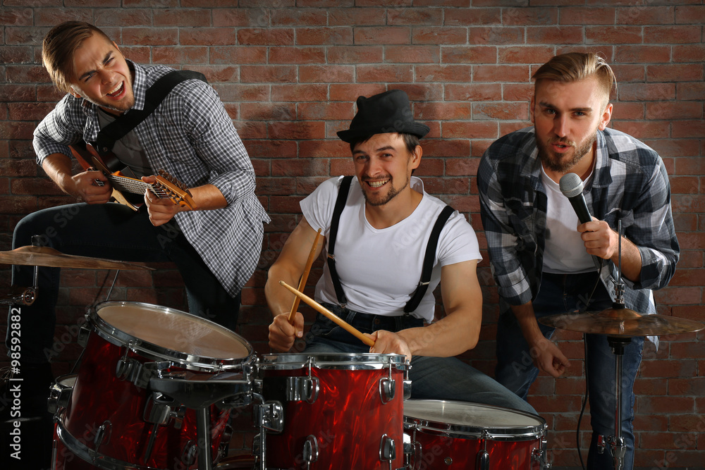 Musicians playing the drums on brick wall background