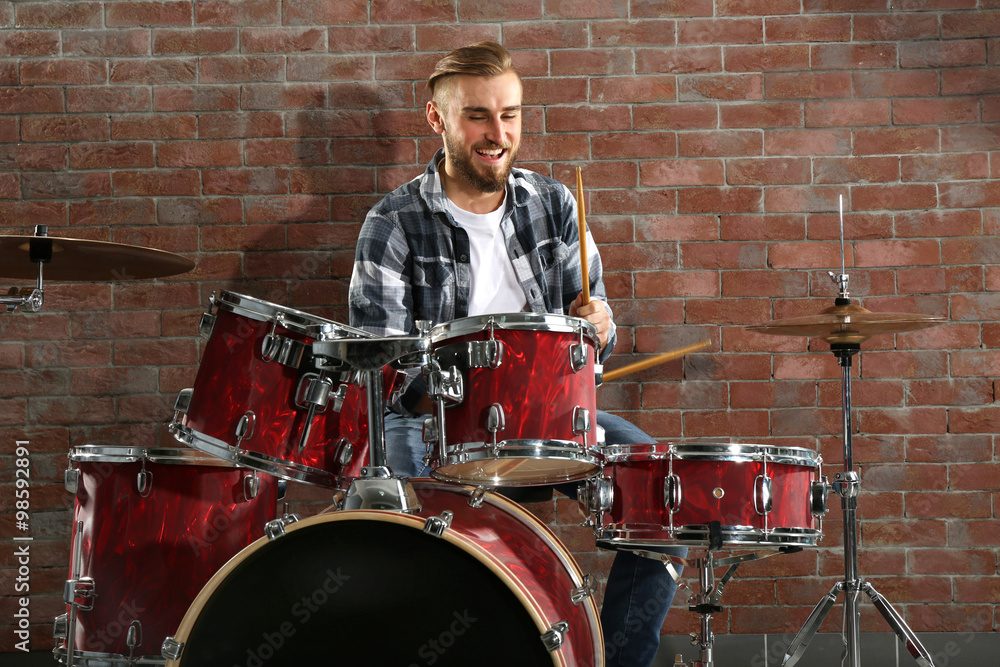 Musician playing the drums on brick wall background