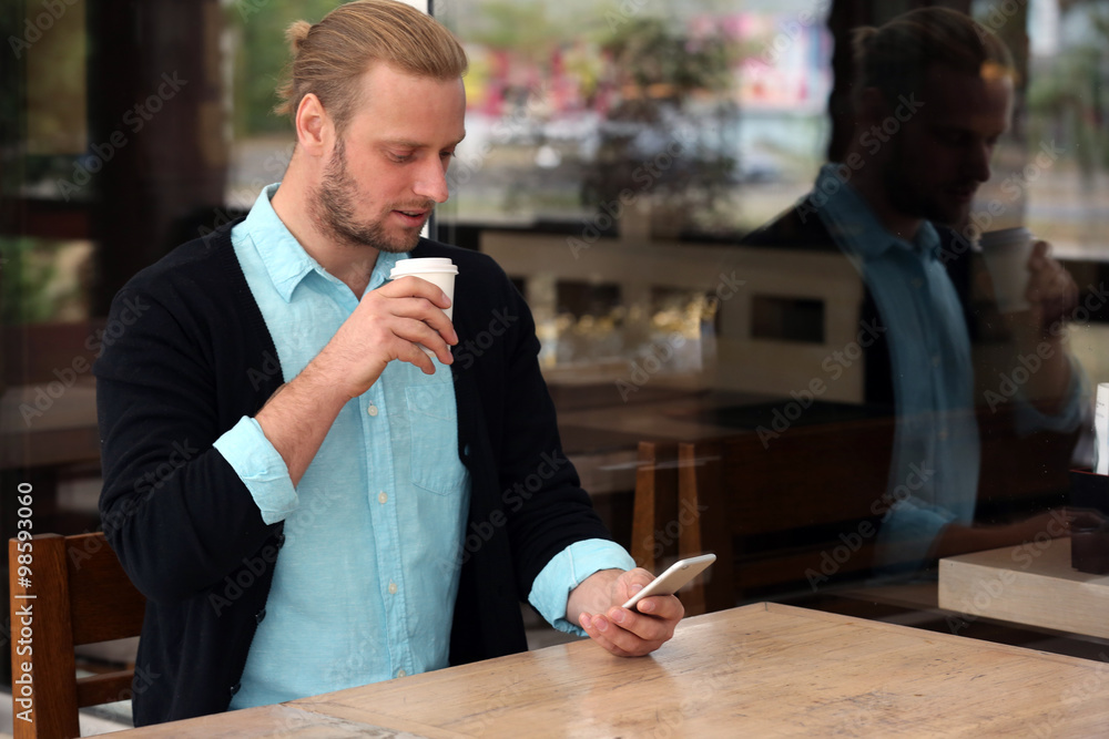Young attractive businessman having lunch and working in a cafe