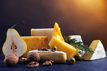 Wall Mural - Different kinds of cheese, pear, nuts and olives, on the table, close up