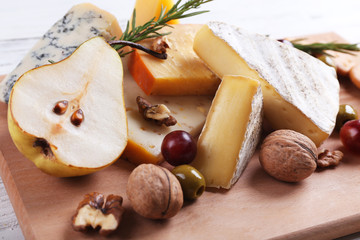 Wall Mural - Different kinds of cheese with fruits and honey on the table, close up