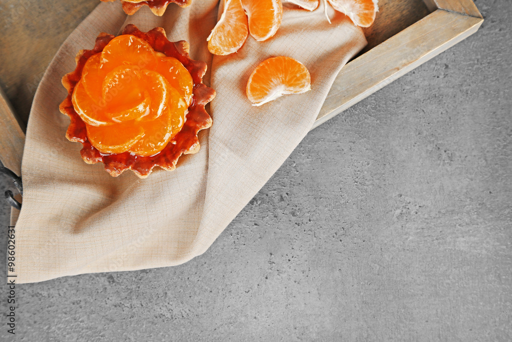 Sweet cakes with tangerines on dark metal table, close up