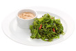 Salad Chuka Seaweed with peanut sauce in a gravy boat on a white plate on a white background