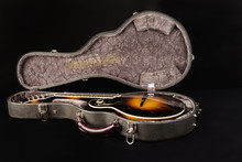 Grey leather case for mandolin on black background.