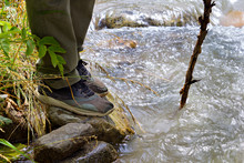 Close Up Of Male Hiking Boots On Hiker  Walking Crossing River Creek