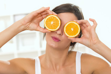 Woman holding oranges in front of her eyes